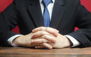 A man sits at the table with folded arms. Ready to listen to news and criticism. Serious talk. Calmly. Communication and body expressions. Job interview. Make an informed decision. Humility. photo