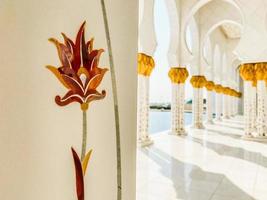 Abu dhabi, UAE, 2022 - close up flowers on columns art exterior details on Grand mosque. Corridors of Grand mosque with nobody in bright sun light photo