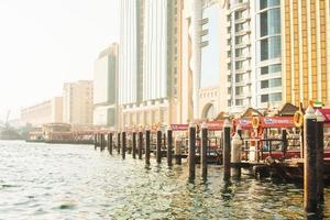 Dubai, UAE, 2022 - vintage boats and ships on river by beautiful new buildings in Dubai creek district in summer photo