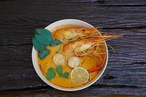 Tom yum kung in a cup on a wooden floor, Tom yum kung is also the national dish of Thailand.  And is a food that is famous all over the world. photo