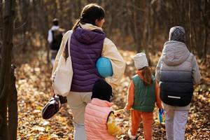 Mother with kids in family leisure at autumn activity in forest. photo