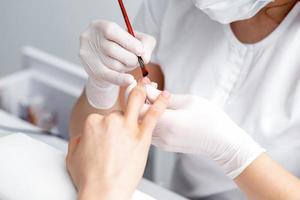 Manicure master applying transparent nail polish photo