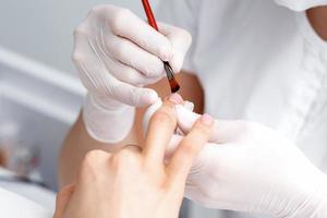 Manicure master applying transparent nail polish photo