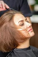 Hand of hairdresser combs hair of young woman photo