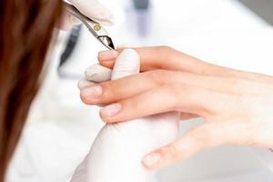 Close up of manicurist using manicure clipper photo