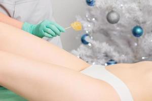 Young woman getting wax epilation of legs photo