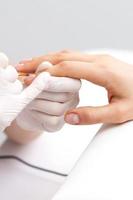 maestro de manicura aplicando esmalte de uñas transparente foto
