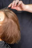 Hand of hairdresser combs hair of young woman photo