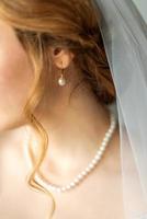 Wedding pearl earring on ear of young bride photo