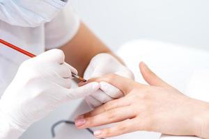 Manicure master applying transparent nail polish photo