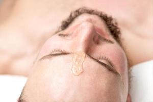 Liquid wax between the eyebrows of a young man photo