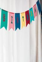 Happy birthday banner party background against white curtains and natural light photo