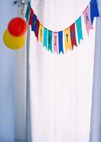 Happy birthday banner party background against white curtains and natural light
