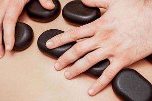 Stone massage on back of man. photo