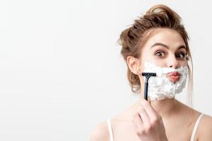 Woman shaving her face by razor photo