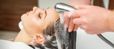 Hands of hairdresser washing hair of woman photo