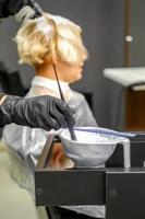 Hairdresser dyeing hair of young woman photo