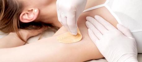 Cosmetologist applying wax paste on armpit photo