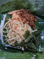 Nasi Kucing, food with small portions typical of Central Java. Contains rice, stir-fried vegetables, usually chickpeas, stir-fried tempeh, soy sauce, and fried noodles. photo