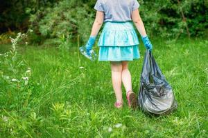 Little girl cleans plastic trash photo