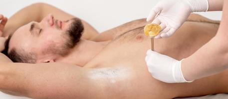 Cosmetologist applying wax paste on armpit photo