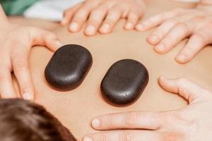 masaje con piedras en la espalda del hombre. foto