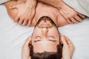 Man receiving head massage by two masseurs photo