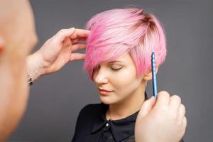 Hairdresser checking woman's pink hairstyle. photo