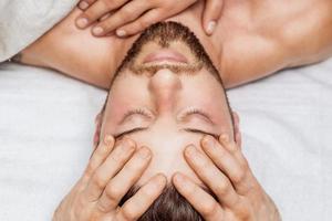 Man receiving head massage by two masseurs photo