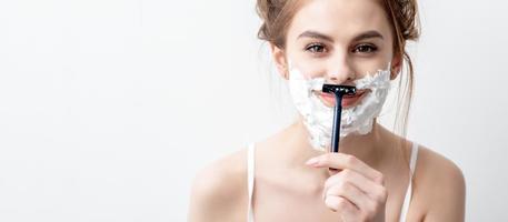 Woman shaving her face by razor photo