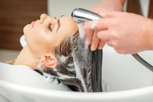 manos de peluquero lavando cabello de mujer foto