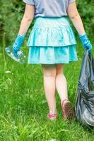 Little girl cleans plastic trash photo