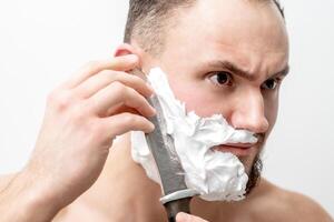 Man shaving beard with knife photo