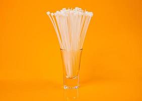 bridas de nailon en vidrio en tarro en balde sobre fondo naranja foto