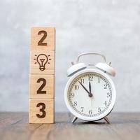 Happy New Year with vintage alarm clock and 2023 block with lightbulb icon. New Start, Business Idea, Creative, Thinking, brainstorm, Goal, Resolution, strategy, plan and Action concepts photo