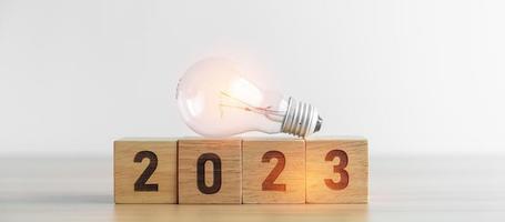 Bloque 2023 con bombilla. idea de negocio, creatividad, pensamiento, lluvia de ideas, objetivo, resolución, estrategia, plan, acción, cambio y conceptos de inicio de año nuevo foto