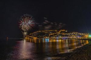 wonderful reflection of night fireworks on the sea and city sea view photo