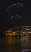 mar nocturno y reflexión de la ciudad y luces de drones foto