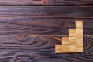 A wooden blocks cube over black wooden textured background with copy space for add word text title. Concept or conceptual Wood block stair or four steps. Cubic photo