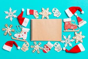 Top view of notebook with Christmas decorations and Santa hats on blue background. Happy holiday concept photo