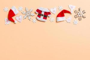 Top view of Christmas decorations and Santa hats on orange background. Happy holiday concept with copy space photo