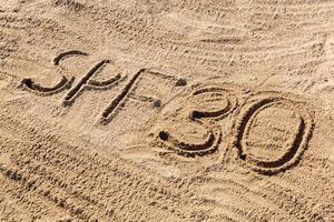 Sun protect factor thirty concept. SPF 30 word written on the beach photo