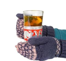Female hands in mittens, holding an old glass with tea. photo