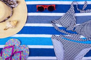 swimsuit with beach accessories on blue background. Sun Glasses Top View Seashell Shorts Flip flops Swimsuit photo