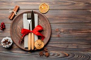 Top view of holiday dinner decorated with dried fruit and cinnamon on wooden background. Set of plate, urensil and New Year decorations. Christmas time concept with epmty space for your design photo