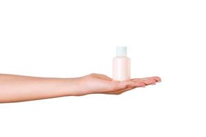 Female hand holding cream bottle of lotion isolated. Girl give tube cosmetic products on white background photo