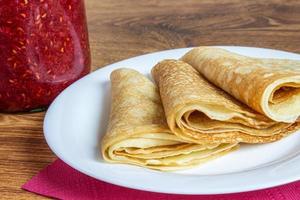 crepé doblado casero fresco relleno de mermelada de fresa en el plato foto