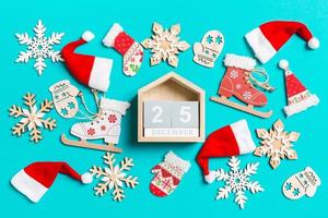 Top view of wooden calendar with Christmas decorations and Santa hats on blue background. The twenty fifth of December. Happy holiday concept photo