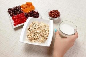 The girl took milk to pour it into oatmeal. Useful and healthy breakfast. White background photo