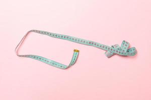 Top view of curled measure tape on pink background. Keeping fit concept photo